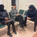 Rosja 2025… Dwójka funkcjonariuszy policji eskortuje perkusistę na rozprawę apel...